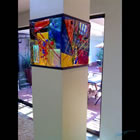 Architectural installation of four lighted art glass panels enclosing a support column section.